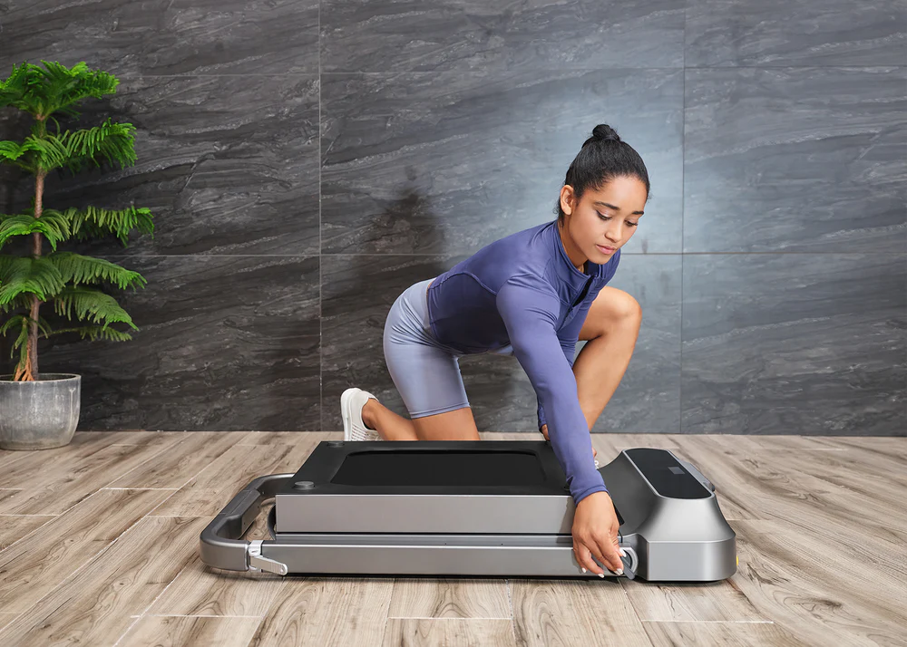 Mujer mostrando cómo la cinta de correr plegable KingSmith R2 se despliega para iniciar el entrenamiento, destacando su facilidad de uso