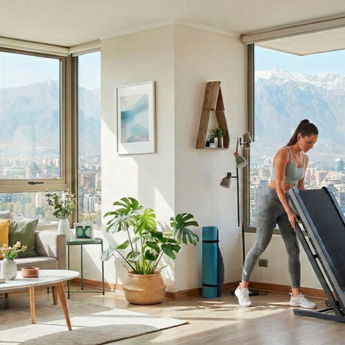 Mujer plegando trotadora en departamento moderno con vista a la cordillera en Chile.