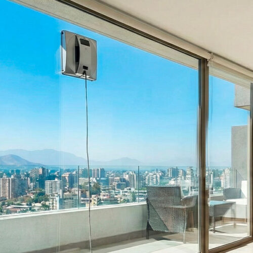 Robot limpia vidrios cuadrado limpiando ventanal de departamento en altura en Santiago.